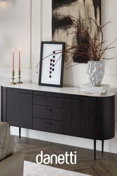 a black and white painting sitting on top of a wooden table next to a vase