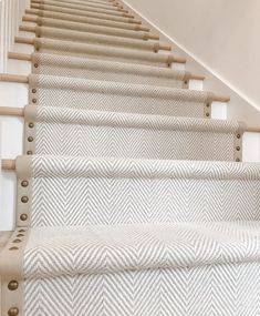 the stairs are lined with white carpet and wooden handrails