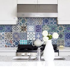 a white vase filled with flowers sitting on top of a kitchen counter next to a stove