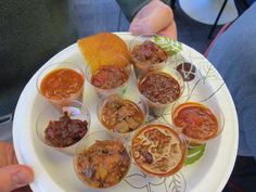 a white plate topped with cups filled with different types of food and sauces on top of it