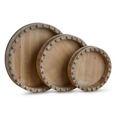 three wooden plates sitting next to each other on top of a white surface with rivets