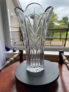 a clear glass vase sitting on top of a wooden table next to a large window