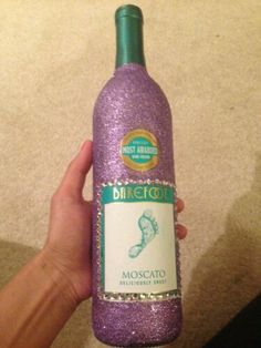 a hand holding a purple wine bottle with glitter on it