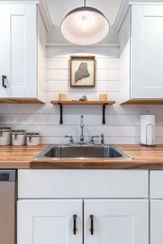 a kitchen with white cabinets and wood counter tops