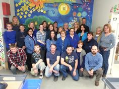 a group of people posing in front of a mural