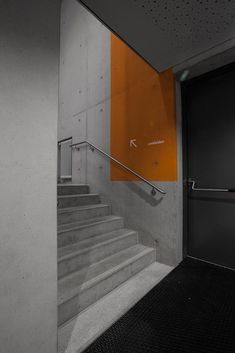 an orange and white sign is on the wall next to some stairs in a building