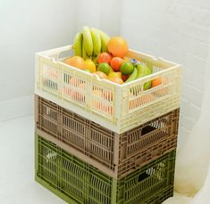 a crate filled with assorted fruit sitting on top of a white floor next to a brick wall