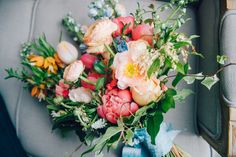 a bouquet of flowers sitting on top of a gray couch next to a blue ribbon