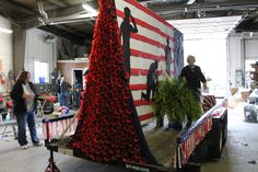 a woman standing next to a large sculpture made out of wine corks and an american flag