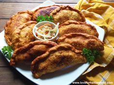 some fried food on a white plate with a side of coleslaw and dipping sauce