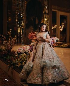 a woman in a wedding dress is standing on the stairs with flowers and greenery behind her