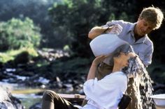 a man is pouring water onto another man's head while he sits on the ground