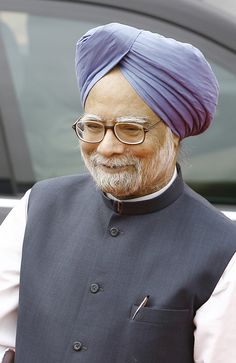 an old man with glasses and a turban standing in front of a car