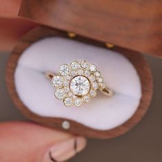 a woman's hand holding a ring in a wooden box with diamonds on it