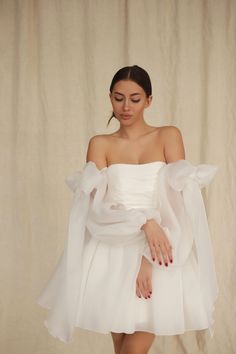 a woman in a white dress posing for the camera with her hands on her hips