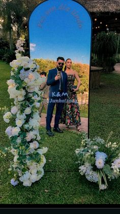 a man and woman taking a selfie in front of a mirror with flowers on it