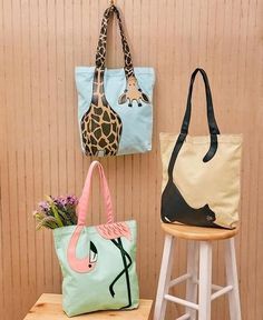 three purses hanging on the wall next to a stool with flowers in it and a giraffe bag