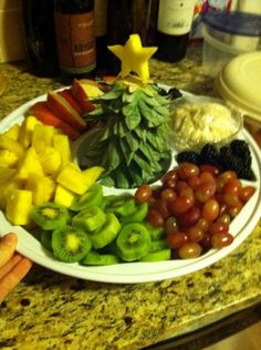 a white plate topped with lots of fruit and veggies next to wine bottles