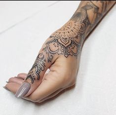 a woman's arm with tattoos on it and her hand holding something in the air