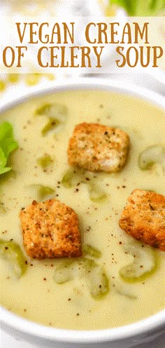 a white bowl filled with soup and croutons on top of green leaves in the background