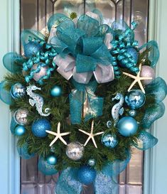 a blue wreath with starfish and ornaments on it is hanging from the front door