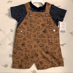 New With Tag - Carter’s 2 Piece Boys Dino Overalls Set. Overalls Are Brown With Navy Blue Dinosaurs And The Top Is A Navy Blue And White T-Shirt. Casual Brown Playwear Sets, Brown Cotton Playwear Set, Spring Cotton Sets With Dinosaur Print, Cute Brown Cotton Set, Cute Dinosaur Print Sets For Summer, Spring Dinosaur Print Playtime Sets, Spring Playtime Dinosaur Print Sets, Cute Fitted Brown Sets, Playful Brown Cotton Sets