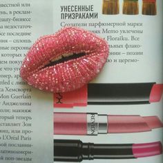 an open magazine with pink lipstick and other cosmetics items on it's page in russian