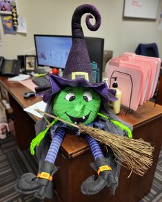 a stuffed witch sitting on top of a desk