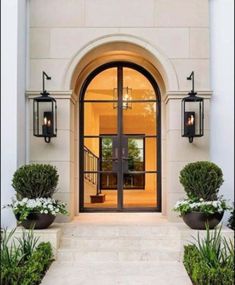 an entrance to a house with two large doors and some planters on the side