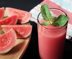 a glass of watermelon juice next to slices of watermelon