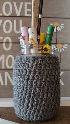 a crocheted jar with pens and pencils in it