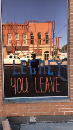 the reflection of a person standing in front of a store window that says, let it fly you leave