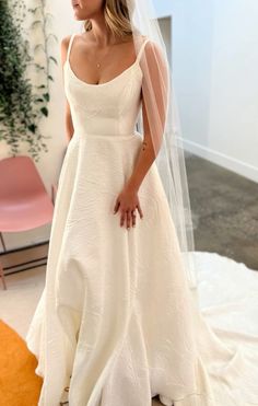 a woman wearing a wedding dress and veil standing in front of a mirror with her hands on her hips