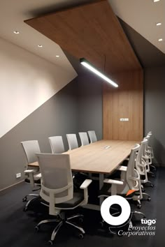 an empty conference room with white chairs and a wooden table in front of a slanted wall