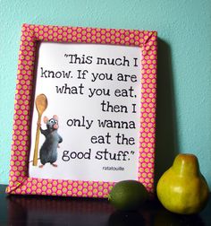 a picture frame with an image of a rat holding a spoon next to two pears