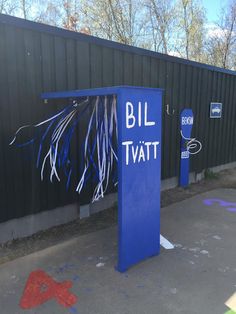 a blue sign that says bill tatt in front of a wall with graffiti on it