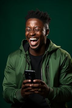 a young man laughing while looking at his cell phone in front of him with an intense look on his face