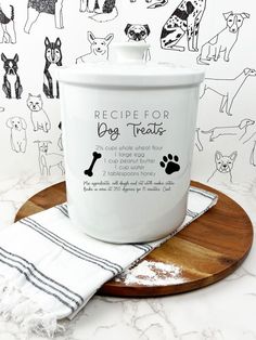 a white dog treat tin sitting on top of a wooden tray next to a black and white wall