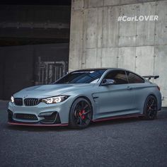 a grey bmw car parked in front of a building with red rims on it