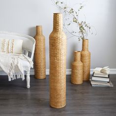 three tall vases sitting next to each other on a wooden floor near a white chair