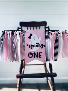 a pink and black birthday banner hanging from a wooden chair