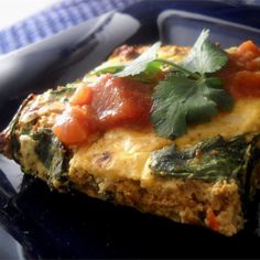 an omelet with tomatoes, cheese and herbs on it