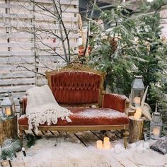 a red couch sitting on top of a wooden floor next to a forest filled with trees