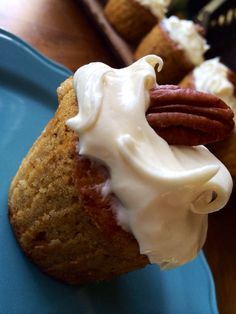 a close up of a pastry on a plate with icing and pecans in the background