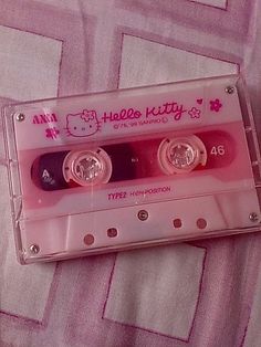 an old hello kitty tape recorder sitting on top of a pink and white bed sheet