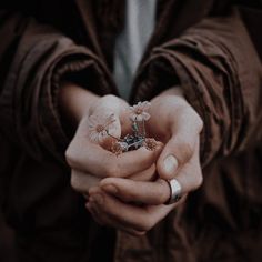 a person holding out their hands with some flowers in it's middle and two fingers on the other hand