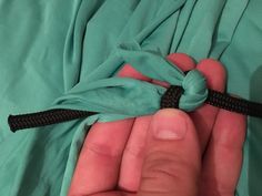 a person holding something in their hand with a knot on it's end,