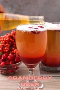 two glasses filled with cranberry beer next to berries