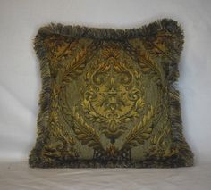 a decorative pillow with fringes on the edges and an ornate design is displayed against a white background