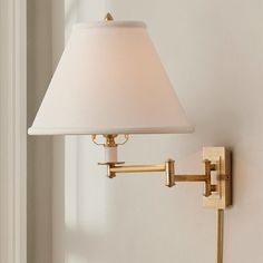 a lamp that is on the wall next to a light fixture with a white shade